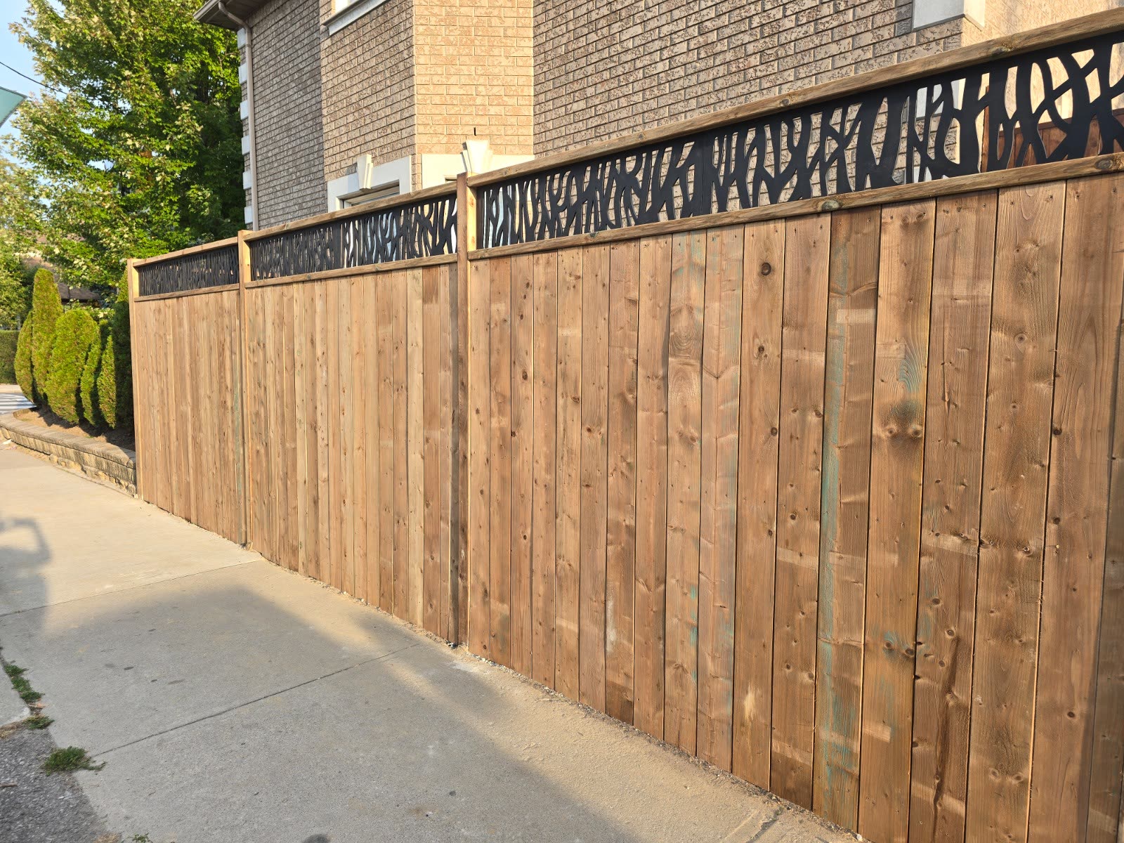 Finished wood privacy fence with decorative metal screen inserts