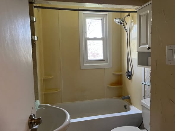 Bathroom before: dated yellow tub surround