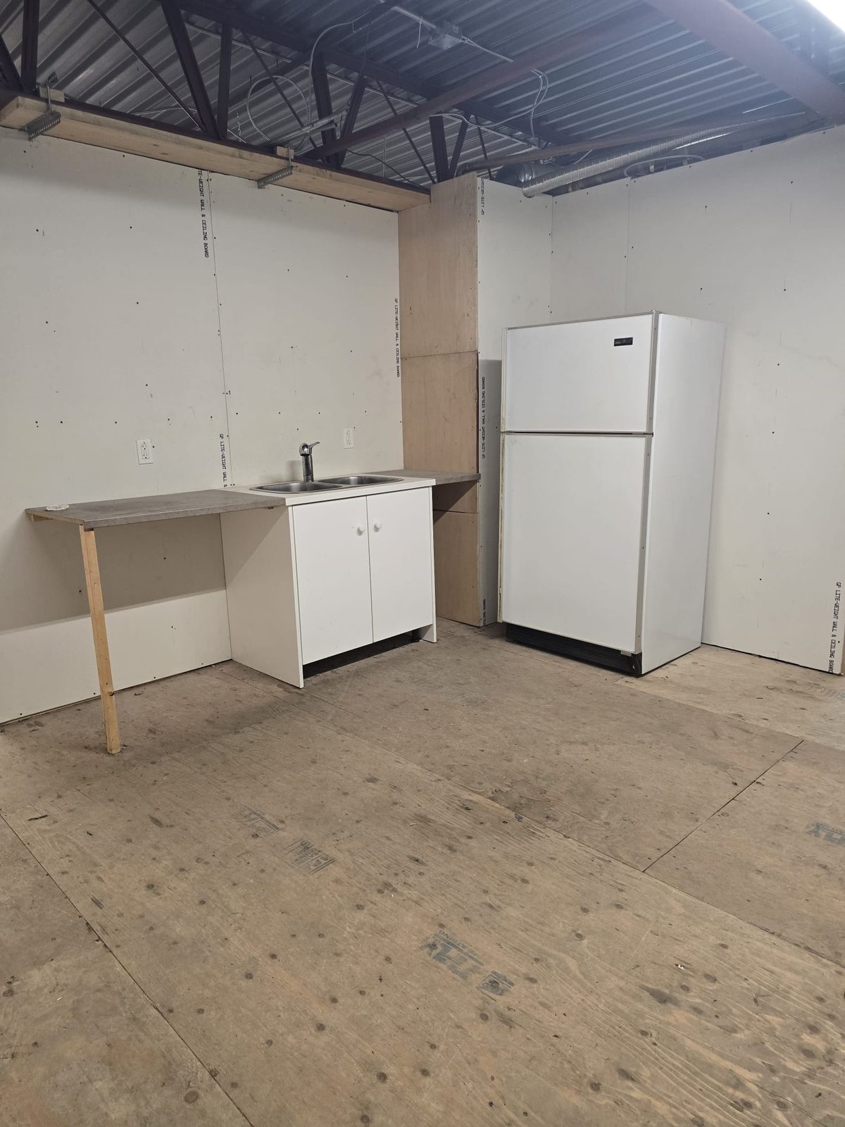 Kitchen before: unfinished drywall, plywood subfloor and a temporary cabinet