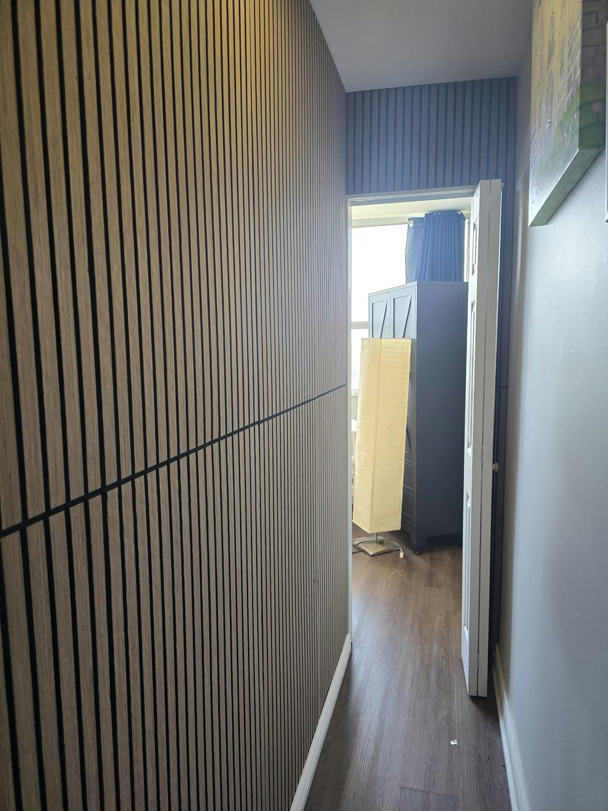 Bedroom after: finished partition with wood-slat accent wall and a door into the second room